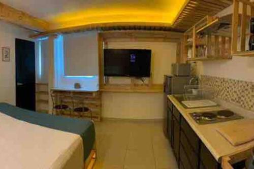 a room with a bed and a kitchen with a television at NUEVO Estudio en Playas Vicente Fox. ¡Excelente ubicación! in Boca del Río