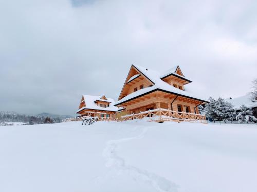 a log cabin covered in snow at Góralskie Domki na Podhalu - z jacuzzi in Maniowy