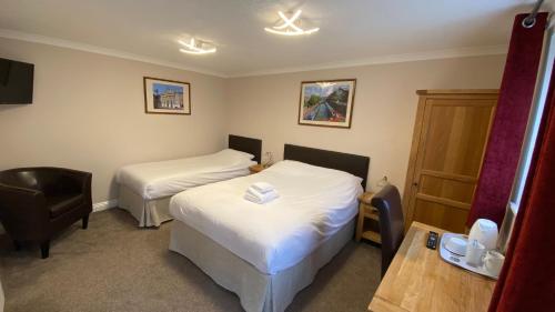 a hotel room with two beds and a chair at Fairlawns Guest House in Banbury