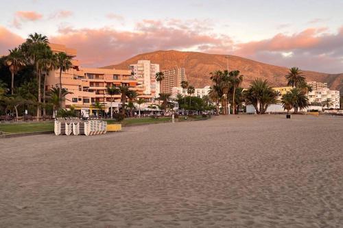 uma praia com palmeiras e edifícios e uma montanha em Estudio La Gavota, vista al mar em Los Cristianos