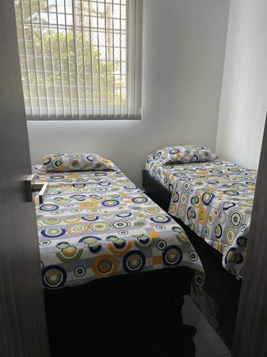 two twin beds in a room with a window at Cali Kamelia Bochalema in Cali