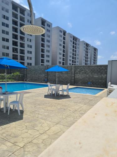 a patio with chairs and umbrellas next to a pool at Cali Kamelia Bochalema in Cali