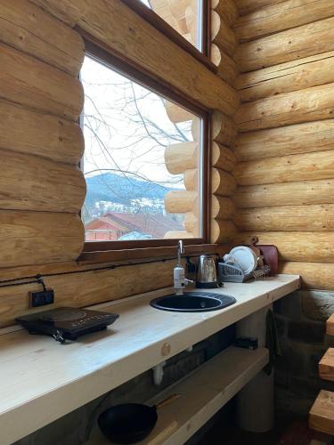 a bathroom with a sink and a window in a log cabin at Chalet PidStromom in Mykulychyn
