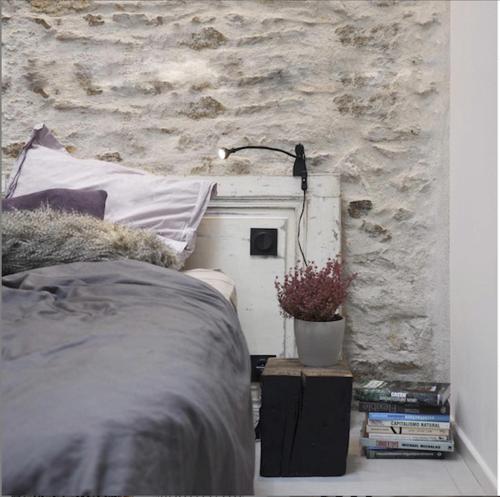 una camera con letto e parete in pietra di Plaisance Appartements & Suites - Bouguenais Apt a Bouguenais