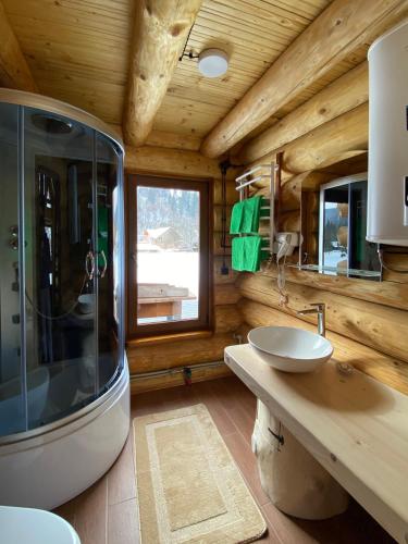 a bathroom with a sink and a shower in a log cabin at Chalet PidStromom in Mykulychyn