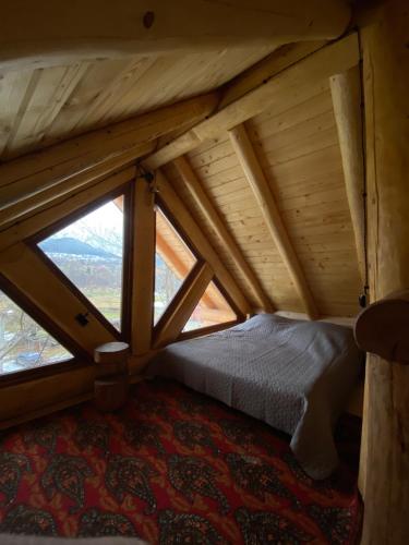 an attic room with a bed and windows at Chalet PidStromom in Mykulychyn