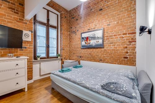a bedroom with a bed and a brick wall at Apartament Uroczy Zakątek in Gliwice