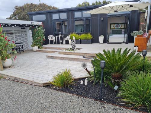 a backyard with a wooden deck with a dog on it at Aroha Tiny House Peka Peka in Waikanae