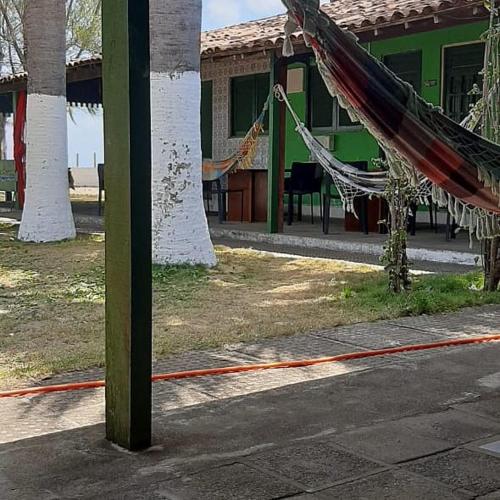 a hammock in front of a house with a building at Pousada Cataventos in Sirinhaém