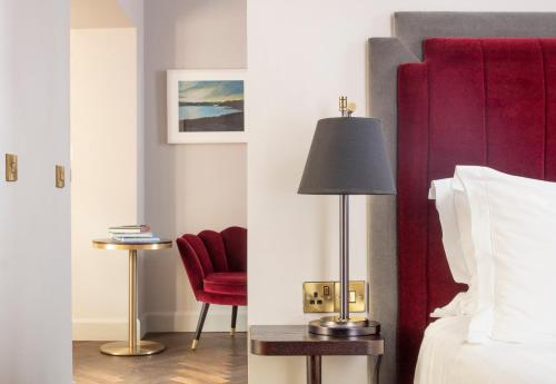 a hotel room with a bed and a red chair at The Wilder in Dublin