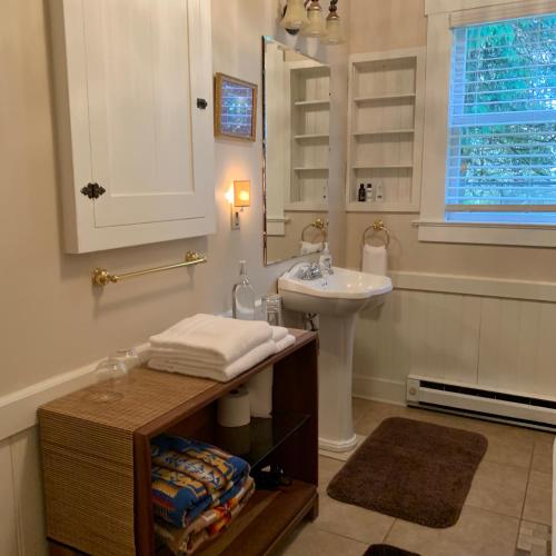 a white bathroom with a sink and a mirror at Mountain Meadows Inn & Chalet Suites in Ashford