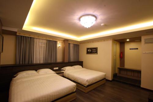 a hotel room with two beds and a light at Shamrock Guest House in Ipoh