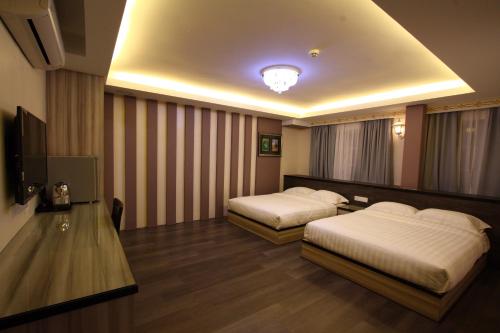 a hotel room with two beds and a television at Shamrock Guest House in Ipoh