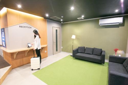 a woman is standing in a room with a suitcase at Playsis Asakusa in Tokyo