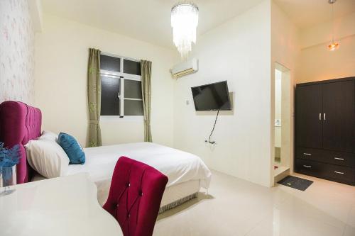a white room with two beds and a tv at Square B&B in Taitung City
