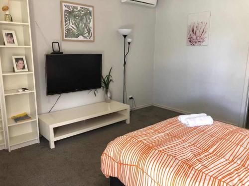 a bedroom with a bed and a flat screen tv at Maddington House Unit C in Perth