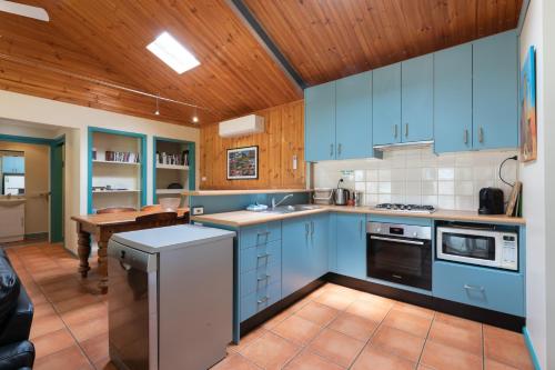 a kitchen with blue cabinets and a wooden ceiling at Banksia Park Cottages in Kangaroo Valley