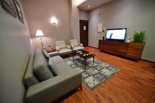 sala de estar con sofá y TV de pantalla plana en سيلين هوم الملقا, en Riad
