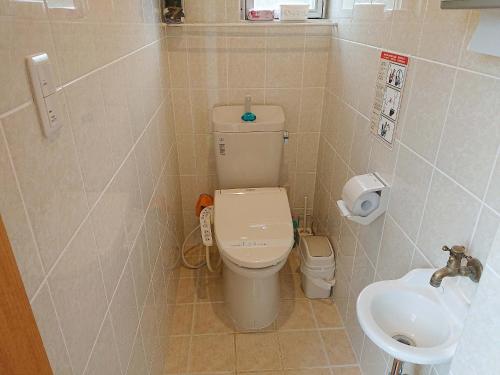 a small bathroom with a toilet and a sink at Kaeruya in Nakijin