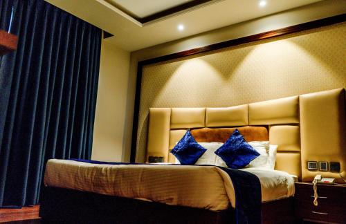 a bedroom with a large bed with blue pillows at juSTa Palampur Resort & Convention Centre in Pālampur