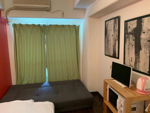 a small room with a bed and a television at Exsaison Shirokita 603 in Osaka