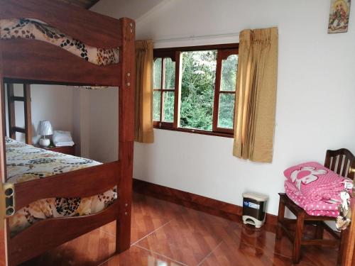 a bedroom with two bunk beds and a chair at Illariy Tampu Ecoalbergue Oxapampa in Oxapampa