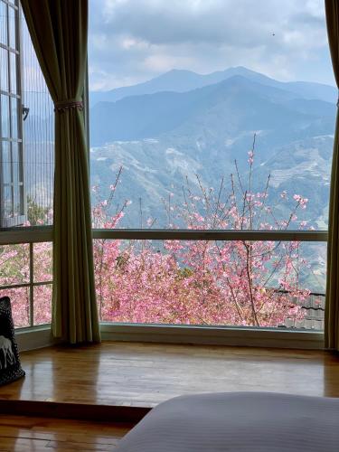 a bedroom with a window with a view of a flowering tree at The Cotswolds Villa in Renai