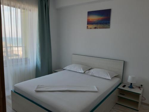 1 dormitorio con cama blanca y ventana en Mamaia Dorin Apartment, en Mamaia