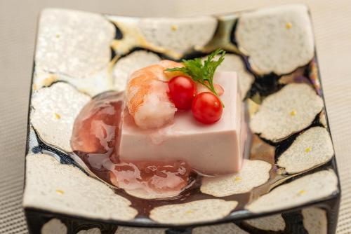 a plate of food with sushi and tomatoes on it at Ishinoya Izunagaoka - TKP Hotels & Resorts in Izunokuni