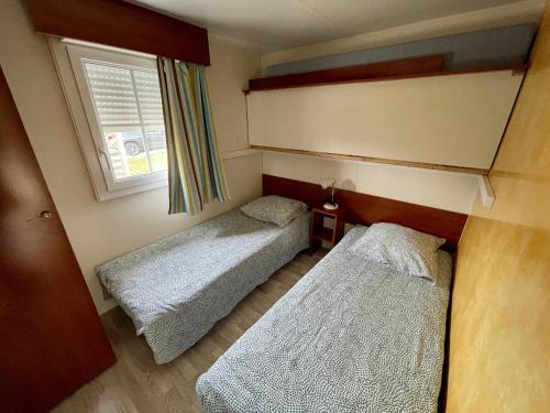 two beds in a small room with a window at Jura mobile home in Marigny