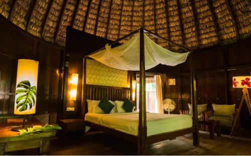 a bedroom with a bed with a canopy at The Barefoot At Havelock in Havelock Island