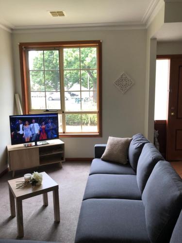 a living room with a blue couch and a tv at Serenity on Sturt in Ballarat