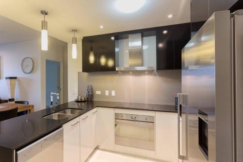 a kitchen with white cabinets and a stainless steel refrigerator at Crocs on Cavenagh in Darwin