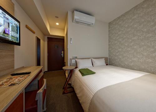 a hotel room with a bed and a flat screen tv at Kuretake Inn Premium Meieki minami in Nagoya