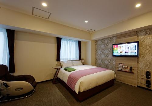 a hotel room with a bed and a flat screen tv at Kuretake Inn Premium Meieki minami in Nagoya