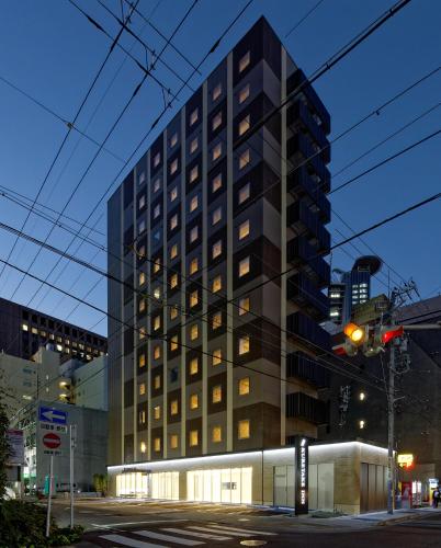 a tall black building with a building at Kuretake Inn Premium Meieki minami in Nagoya