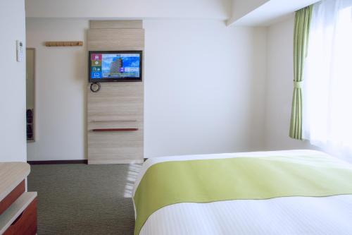 a bedroom with a bed and a flat screen tv at Kuretake Inn Premium Meieki minami in Nagoya