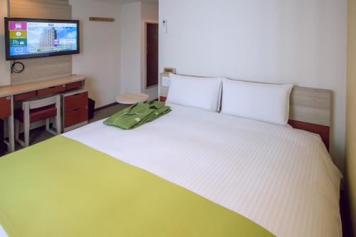 a bedroom with a bed with a green bag on it at Kuretake Inn Premium Meieki minami in Nagoya