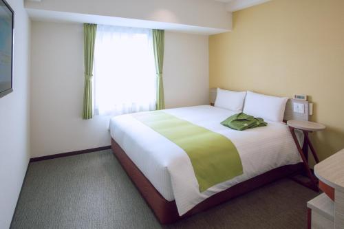 a hotel room with a large bed and a window at Kuretake Inn Premium Meieki minami in Nagoya
