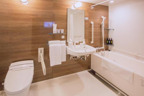 a bathroom with a toilet and a sink and a tub at Kuretake Inn Premium Meieki minami in Nagoya