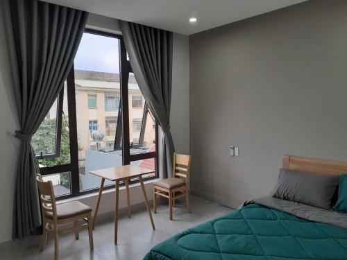 een slaapkamer met een bed, een tafel en een raam bij Duc Hanh Apartment in Da Nang