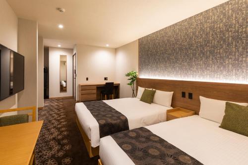 名古屋市にあるグランドベース名古屋-千代倉-のベッド2台とデスクが備わるホテルルームです。