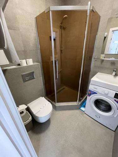 a bathroom with a shower and a toilet and a washing machine at Arcadia apartment & sea terrace in Odesa