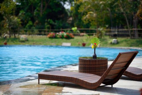 two wicker chairs sitting next to a swimming pool at Jungle Villa Resort - Near Chitwan National Park in Chitwan