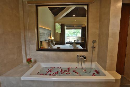 a bathroom with a bath tub with a mirror at Jungle Villa Resort - Near Chitwan National Park in Chitwan