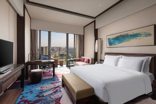 a bedroom with a bed and a desk and a television at Crowne Plaza Chongqing New North Zone by IHG in Chongqing