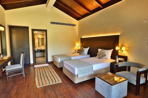 a hotel room with two beds and a desk and chair at Jungle Villa Resort - Near Chitwan National Park in Chitwan