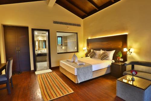 a bedroom with a large bed and a living room at Jungle Villa Resort - Near Chitwan National Park in Chitwan