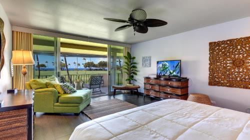 a bedroom with a bed and a chair and a television at Maui Eldorado - J207 in Lahaina