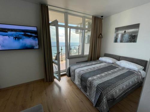 a bedroom with a bed and a large window at Arcadia apartment & sea terrace in Odesa